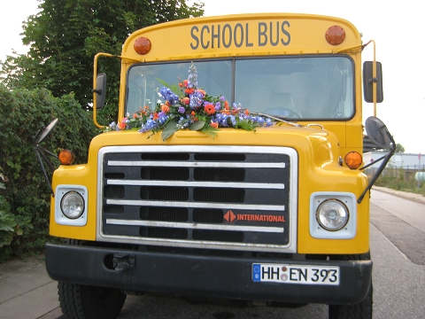 Schulbus mit Blumenbouquet auf Kühlerhaube für Hochzeiten